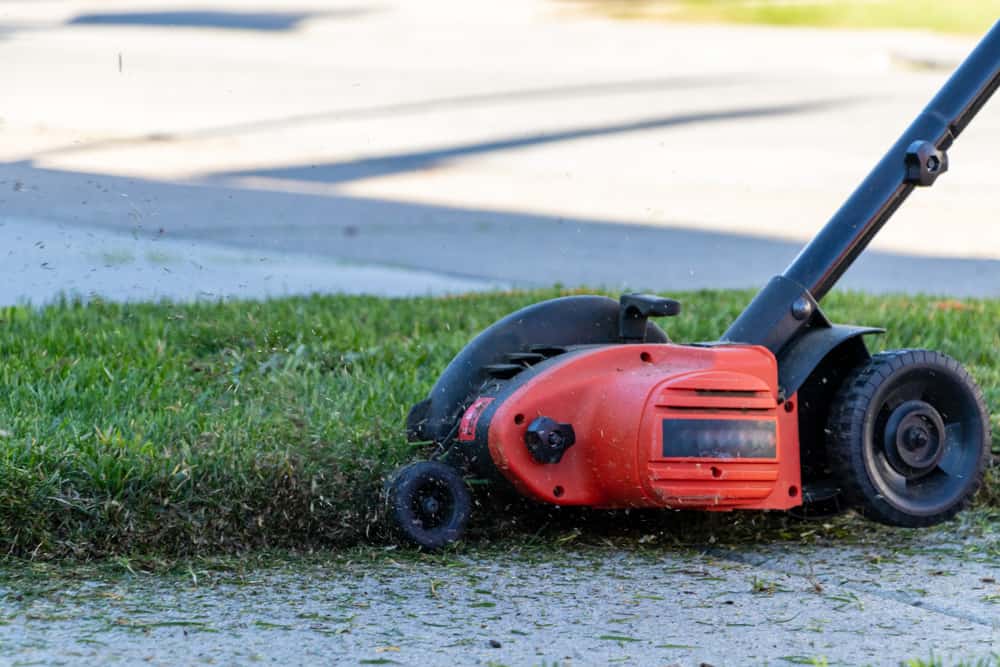 Close-up of landscape edger in action along sidewalk